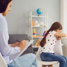 Psychotherapeutin unterhält sich mit einem Kind, welches ihr den Rücken zudreht